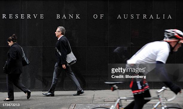 Pedestrians and a cyclist go past the Reserve Bank of Australia headquarters in the central business district of Sydney, Australia, on Monday, July...