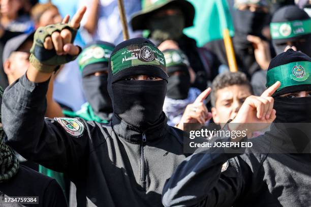 Masked men wearing bandanas showing the name and sigil of the Izzedine al-Qassam Brigades, the military wing of the Palestinian Islamist Hamas...