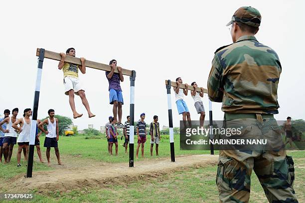 Indian army officer watches candidates perform pull-ups during a physical fitness test at an Indian Army recruitment rally at Khasa, some 15 Kms from...