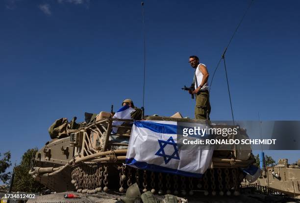 An Israeli soldier stands on top of a Merkava tank positioned outside Kibbutz Beeri near the border with the Gaza Strip on October 20 amid the...