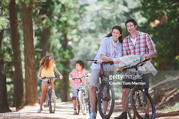 family with bicycles looking at map in woods - lost generation stock pictures, royalty-free photos & images