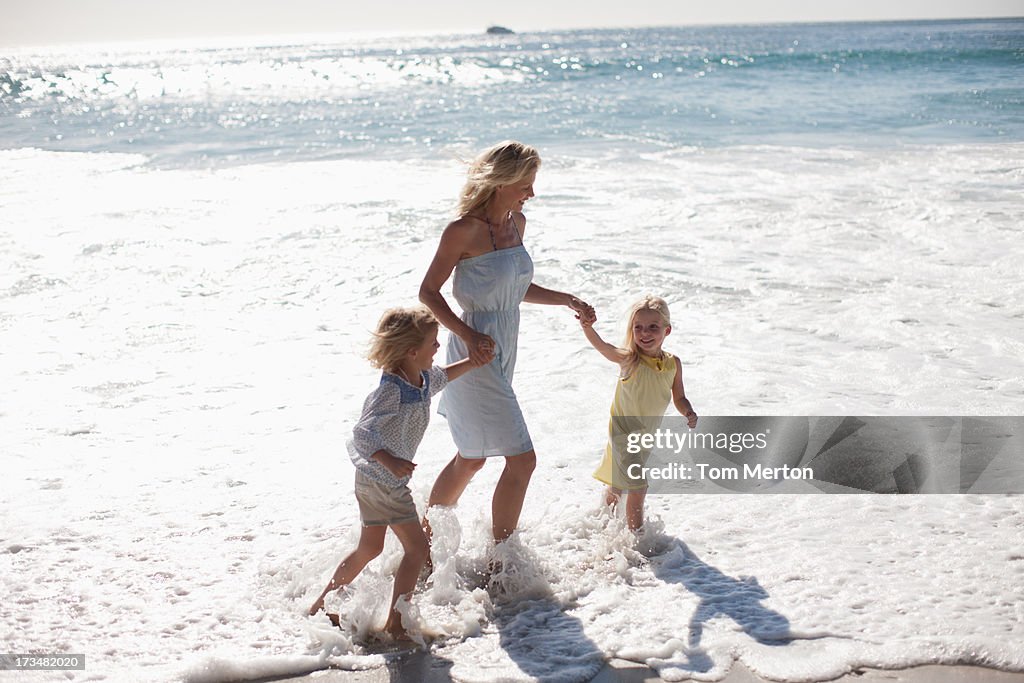 Mother and daughters running on beach