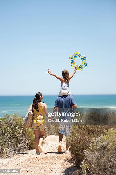 family walking on beach path toward ocean - tote bag stock pictures, royalty-free photos & images