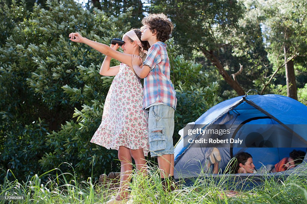 Crianças com binóculos e os pais pôr na Tenda