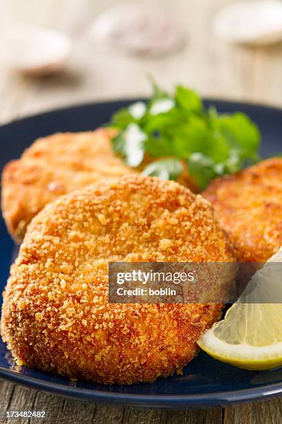crab cakes on a blue plate with lemon wedge - fish cakes stock pictures, royalty-free photos & images