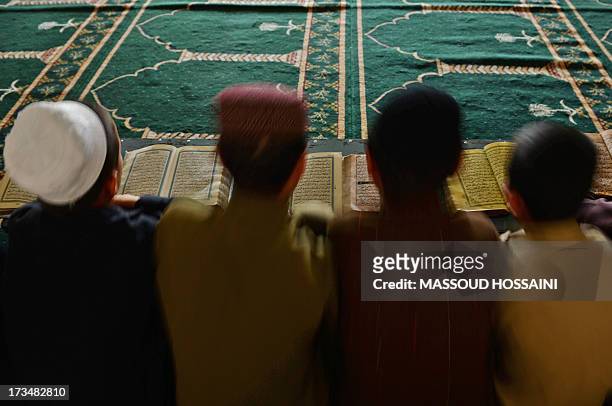 Afghan boys learn and memorize Koran at a Madrassa during the month of Ramadan in Kabul on July 15, 2013. Throughout the month, devout Muslims must...