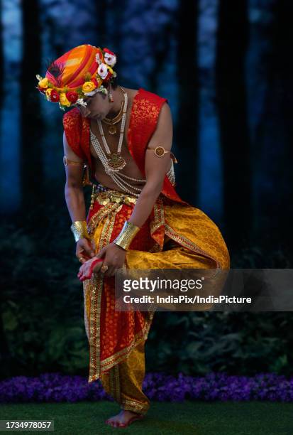 young man dressed up as lord krishna, removing thorn from his foot - indian removal act stockfoto's en -beelden