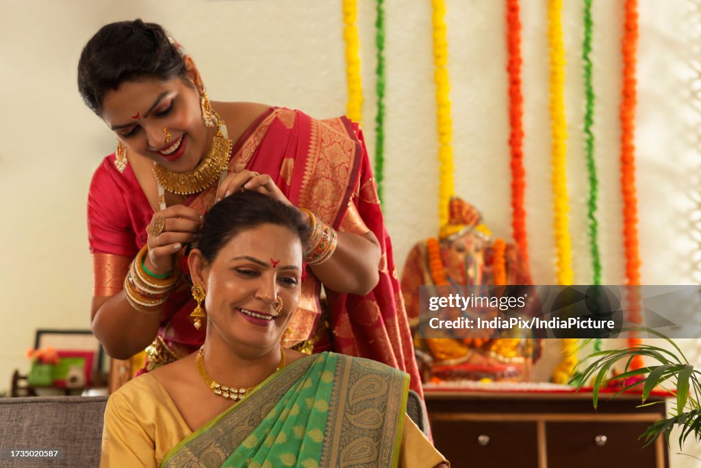 Daughter-in-law helping her mother-in-law while getting ready on the occasion of Ganesh Chaturthi