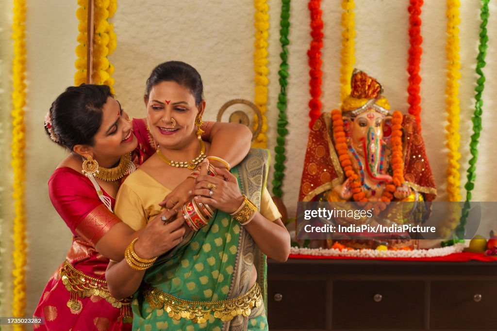 Daughter-in-law embracing her mother-in-law in front of Ganesh idol