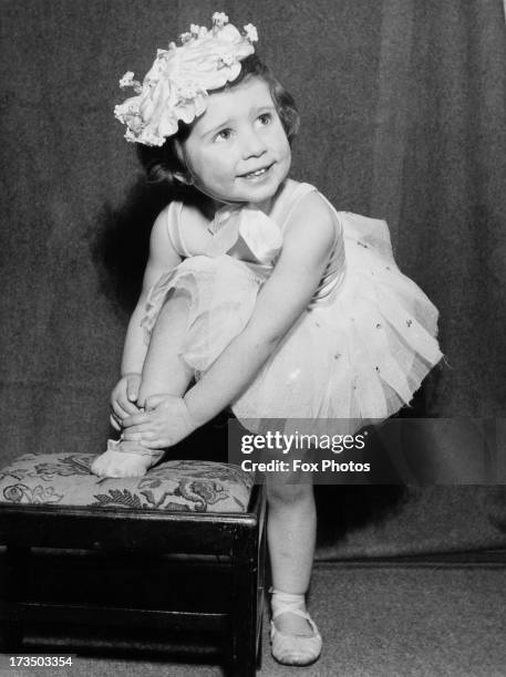 Two year-old aspiring ballerina Rosemary Hoffman ties her shoe before ballet practice near her home in Teddington, London, 28th February 1953.