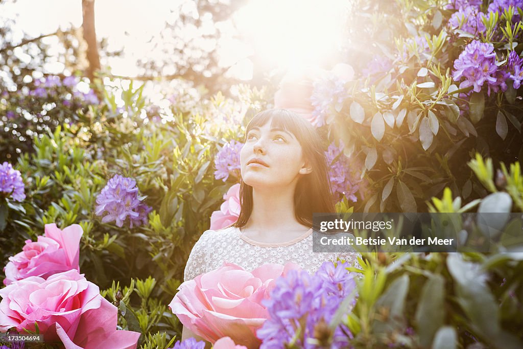 Woman standing in between giant flower bush.