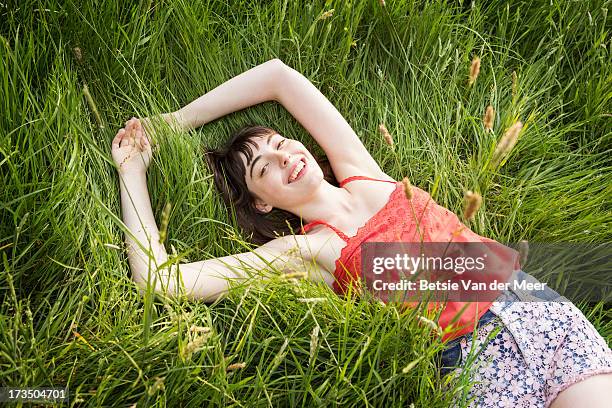 woman laying in grass, smiling. - ärmelloses oberteil stock-fotos und bilder