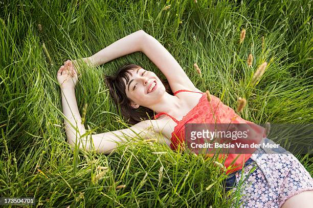 woman laying in grass, smiling. - grass overhead stock pictures, royalty-free photos & images