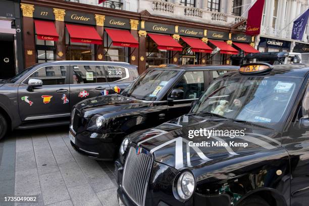 London black cab taxis outside the Cartier store on Bond Street on 16th October 2023 in London, United Kingdom. Bond Street is one of the principal...