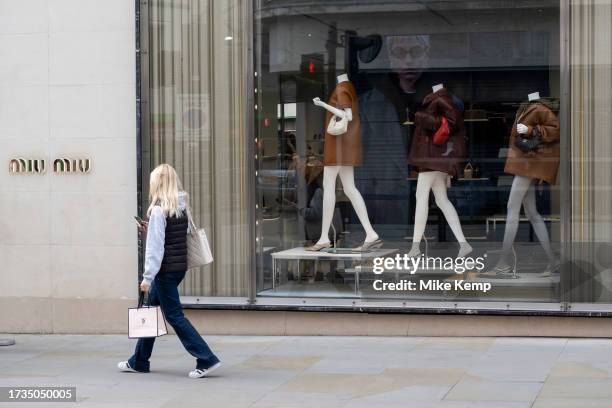 People interacting with the legs of mannequins in the shop window of Miu Miu on Bond Street on 16th October 2023 in London, United Kingdom. Bond...