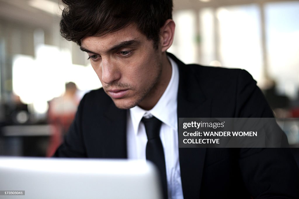 Young businessman in suit on computer in office