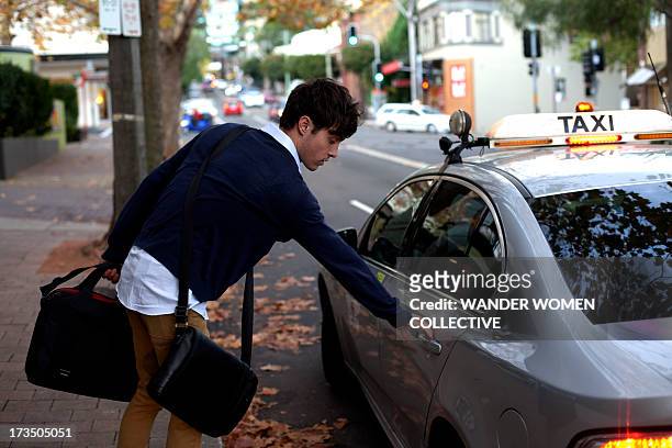 young man catching cab from work in sydney - australia taxi stock pictures, royalty-free photos & images