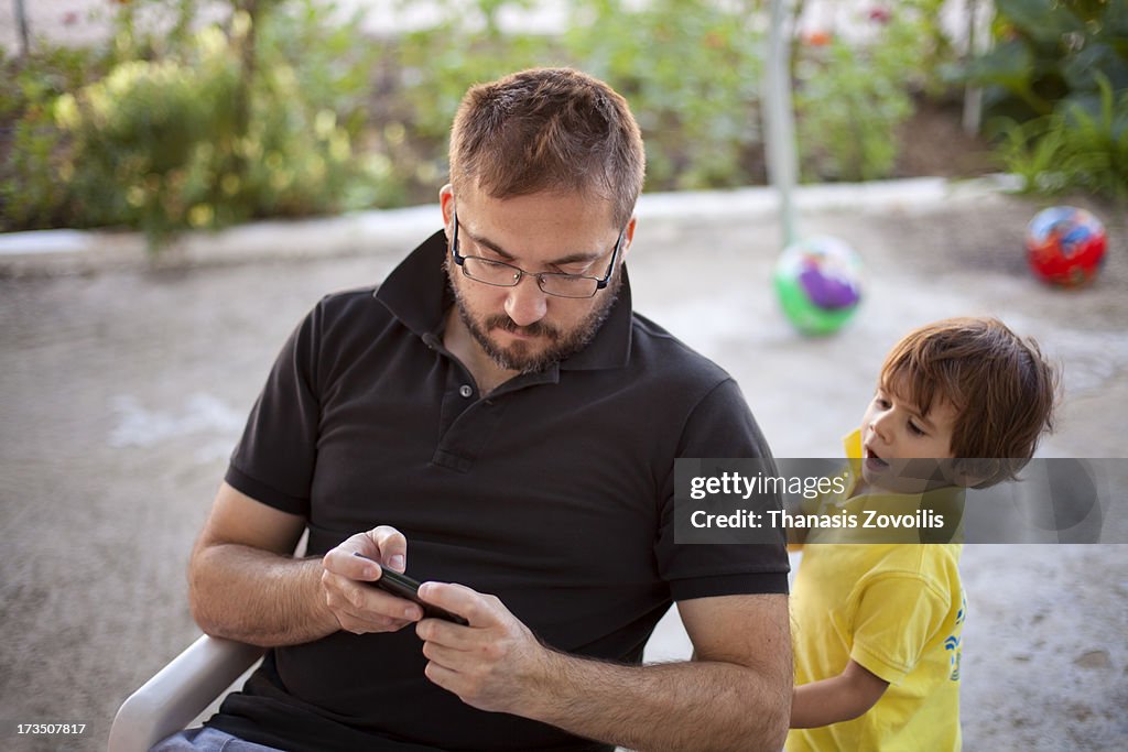 Small boy with his father looking a mobile phone