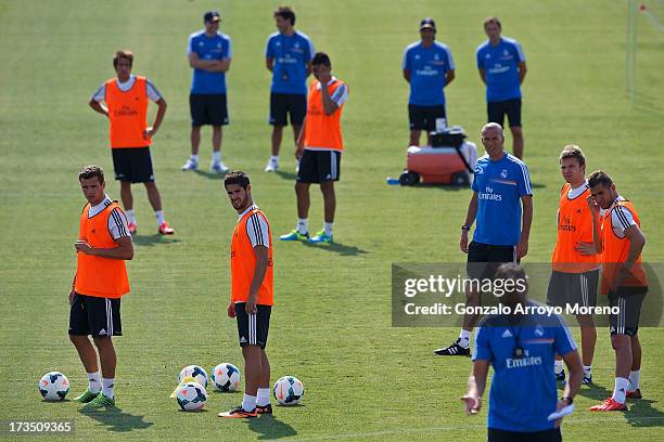 Isco of Real Madrid and his teammates Nacho , Karim Benzema , Asier Illarramendi and head coach Zinedine Zidane listen to a Real madrid coach during...