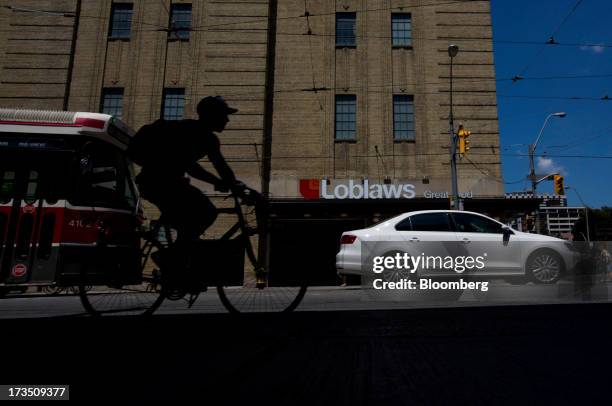 Bicyclist rides past a Loblaw Cos. Store in Toronto, Ontario, Canada, on Monday, July 15, 2013. Loblaw Cos. Agreed to buy Shoppers Drug Mart Corp....