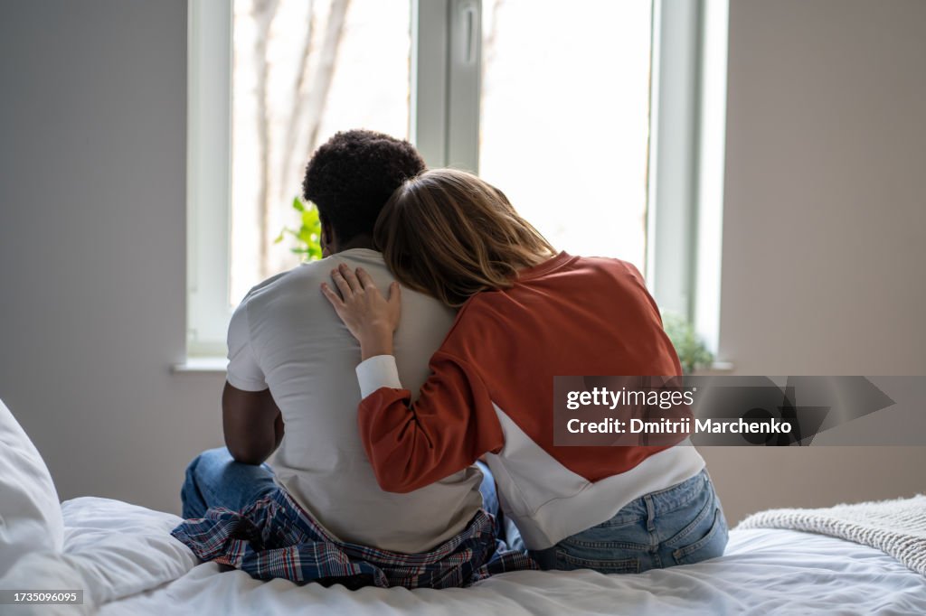Woman putting head on man shoulder for support, comforting and consolation while looking at window