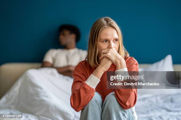 unhappy multiracial couple in bed having problems and misunderstanding after quarrel, argument - resolve conflict stock pictures, royalty-free photos & images