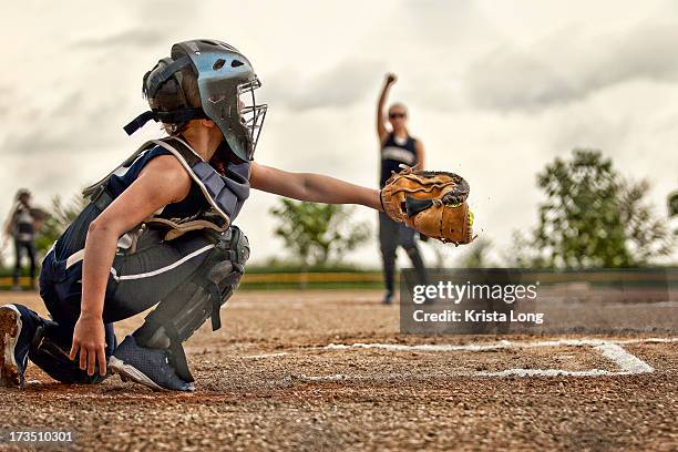 a softball catcher shown catching a pitch - softball sport stock-fotos und bilder