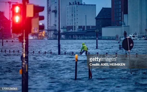 Man makes his way across a flooded street in Flensburg, norhtern Germany on October 20, 2023 as Storm Babet caused havoc.