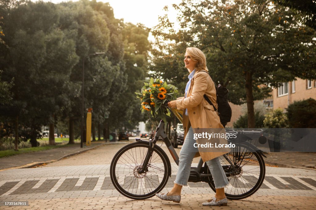 Beautiful woman cycling with sunflowers in Autumn