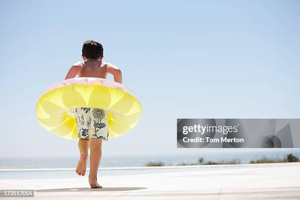 boy with inflatable ring stepping out of infinity pool - ankle deep in water stock pictures, royalty-free photos & images