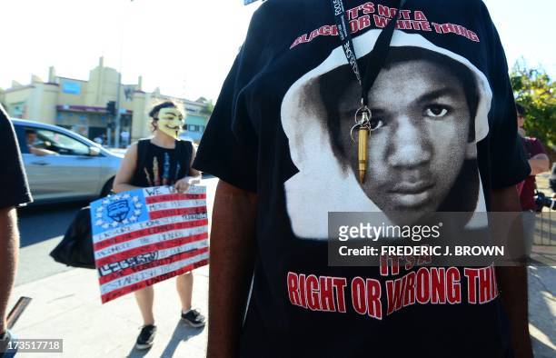 Man wears a single bullet around his neck over his Trayvon t-shirt as people hold placards and shout slogans during a rally in Los Angeles in the...