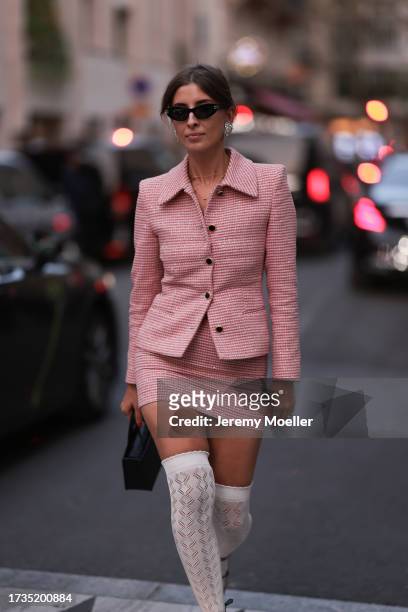 Mina Habchi is seen wearing a pink blazer, a pink short skirt, white knit overknees with lace, black patent high heels, black sunglasses, silver...