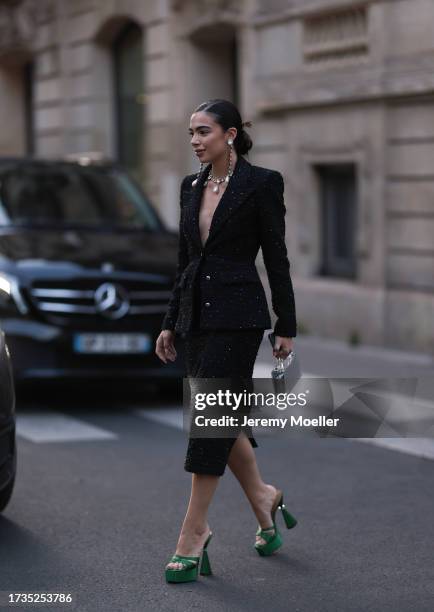 Fashion Week Guest is seen wearing a black blazer with shoulder pads, gold buttons and silver details, a black midi skirt, green high heels with...