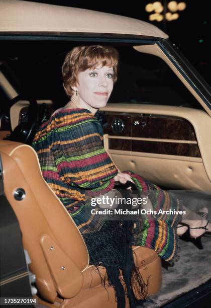 American comedian, actress and singer Carol Burnett with a black shawl over her arm, sitting in the front passenger seat of a car outside the Century...