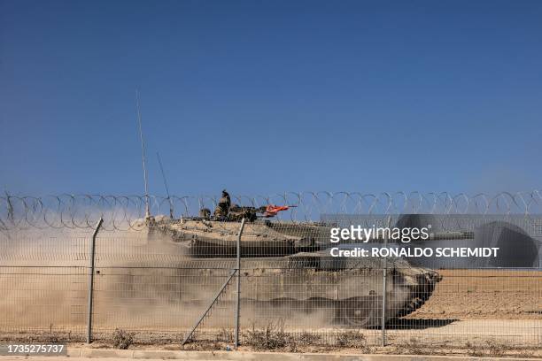 An Israeli Merkava tank drives past a fence near Kibbutz Beeri, close to the border with Gaza on October 20 in the aftermath of an attack by...