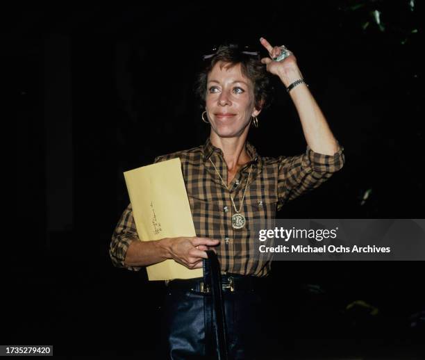 American comedian, actress and singer Carol Burnett, wearing a brown-and-black checked shirt, a large circular pendant hangs from her necklace, an...