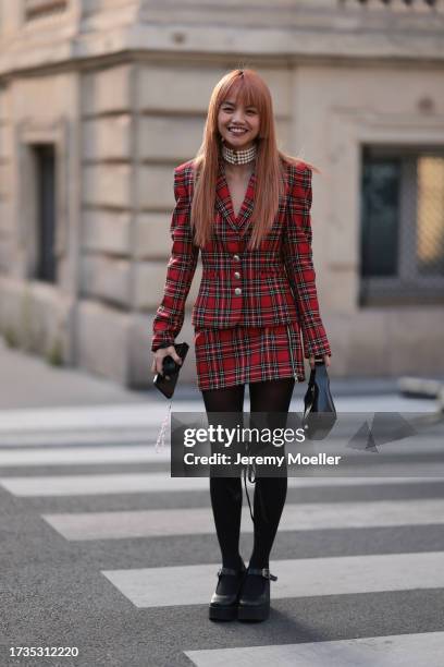 Mia Fa Wells is seen wearing a black red checkered blazer, a black red checkered skirt, black tights, black high heels, multi-layered pearl necklace...