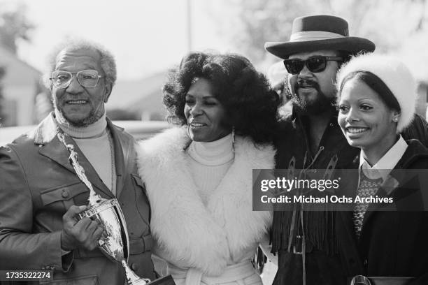 American comedian Redd Foxx, holding a trophy, and his wife, American dancer and showgirl Betty Jean Harris, with American singer Ronald Townson and...