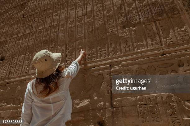 a tourist examines ancient hieroglyphics  at the edfu temple in egypt. - temple stock pictures, royalty-free photos & images