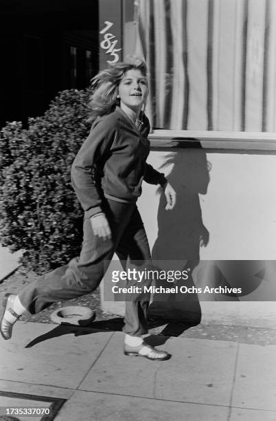 Young girl wearing a leisure suit and jelly sandals running in Los Angeles, California, November 1979.