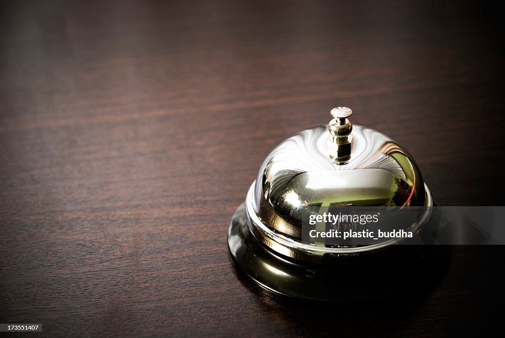 Close up of silver service bell on dark wooden desk