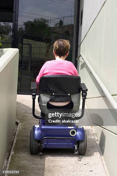 a lady going down a ramp in a motorized wheelchair - wheelchair ramp stock pictures, royalty-free photos & images