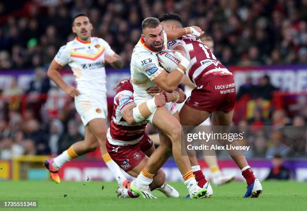 Mike McMeeken of Catalans Dragons is tackled by Tyler Dupree and Kai Pearce-Paul of Wigan Warriors during the Betfred Super League Final match...