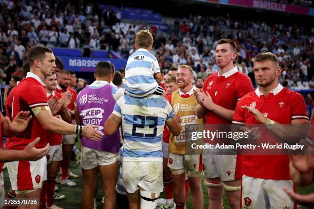 Matias Moroni of Argentina celebrates with his child as Wales players applaud the team following the team's victory during the Rugby World Cup France...