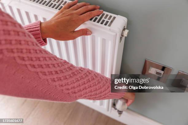 woman's hands adjusting a heating temperature on a radiator at home - heating home stock pictures, royalty-free photos & images