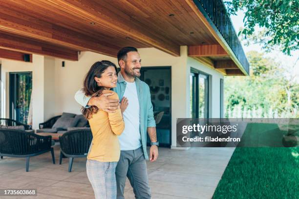 embraced couple in front of their new house - homeowner stock pictures, royalty-free photos & images