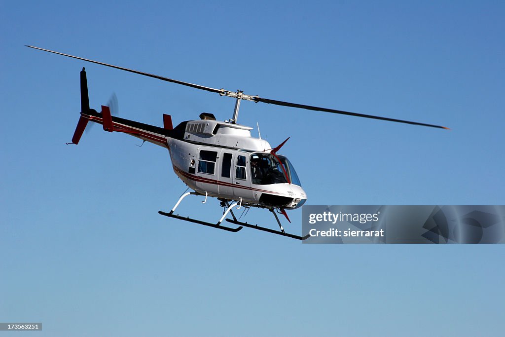 A Bell Ranger helicopter flying on a clear day
