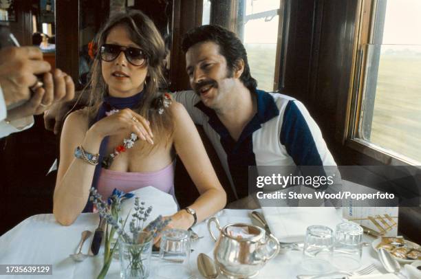 English rock musician Eric Clapton with girlfriend, model and photographer Pattie Boyd seated in the restaurant carriage on a train in Germany, circa...