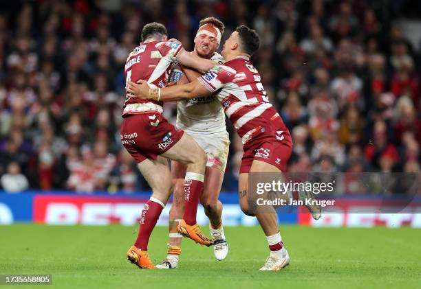 Paul Séguier of Catalans Dragons is tackled by Jake Wardle and Tyler Dupree of Wigan Warriors during the Betfred Super League Final match between...