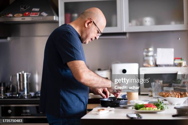 homme d’âge moyen préparant de la nourriture à la maison - régime faible en glucides photos et images de collection